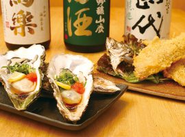 殻付き生牡蠣やアジフライなど、新鮮な魚介類を使った料理を日本酒と共に